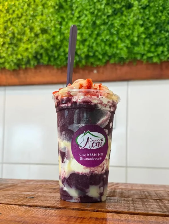 Copo de açaí com morango e creme no topo, sobre bancada clara